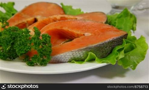 Fresh salmon stake and red caviar on plate. In the background pancakes - a symbol of the Orthodox Shrove Tuesday. Tracking shot