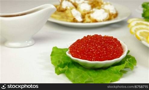 Fresh salmon stake and red caviar on plate. In the background pancakes - a symbol of the Orthodox Shrove Tuesday. Tracking shot