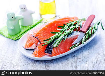 fresh salmon with rosemary on plate and on a table