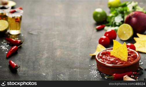 Fresh salsa dips with nachos chips and ingredients on old background. Space for text