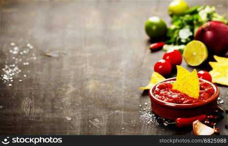 Fresh salsa dips with nachos chips and ingredients on old background. Space for text