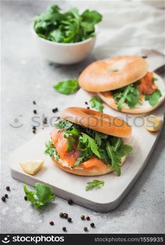 Fresh sandwiches with salmon and bagel, cream cheese and wild rocket in white bowl on light kitchen table