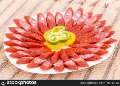 Fresh sausages and peppers in plate on bamboo mat background.