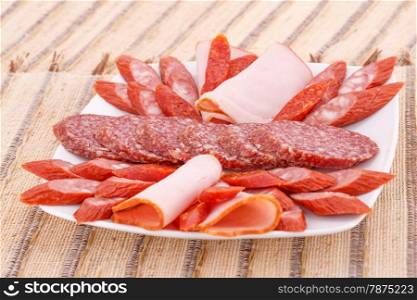 Fresh sausages in plate on bamboo mat background.
