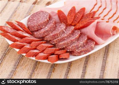 Fresh sausages in plate on bamboo mat background.