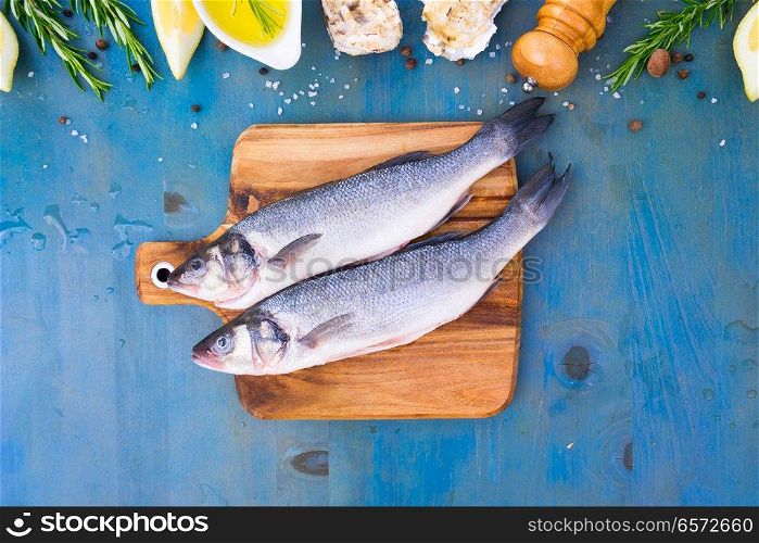 fresh sea fish preparation - top view of two raw seabass fish on cutting board. fresh sea fish preparation