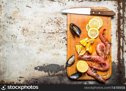 Fresh seafood. Cutting Board with shrimp, shellfish and lemon. On rustic background .. Fresh seafood. Cutting Board with shrimp, shellfish and lemon.