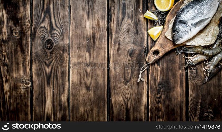 Fresh seafood. Sea fish with lemon slices on a cutting Board. On wooden background.. Sea fish with lemon slices on a cutting Board.