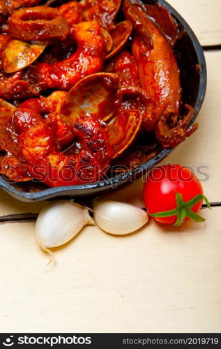 fresh seafood stew prepared on an iron skillet ove white rustic wood table