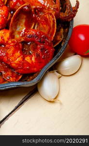 fresh seafood stew prepared on an iron skillet ove white rustic wood table