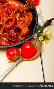 fresh seafood stew prepared on an iron skillet ove white rustic wood table