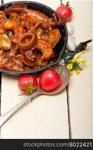 fresh seafood stew prepared on an iron skillet ove white rustic wood table