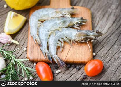 fresh shrimp on wooden cutting board with ingredients herb and spices for cooking seafood / raw shrimps prawns