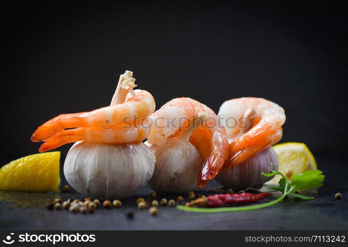 fresh shrimps on garlic served on plate / seafood boiled peeled shrimp prawns cooked with spices lemon chilli and on black background , selective focus