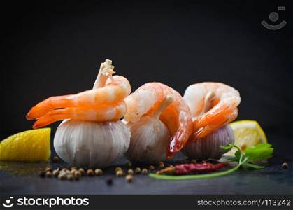 fresh shrimps on garlic served on plate / seafood boiled peeled shrimp prawns cooked with spices lemon chilli and on black background , selective focus
