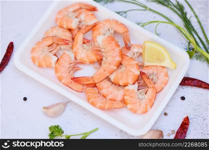 Fresh shrimps on on plate plastic tray with herbs and spices lemon chili on white background, boiled shrimp prawns cooked food in the seafood restaurant
