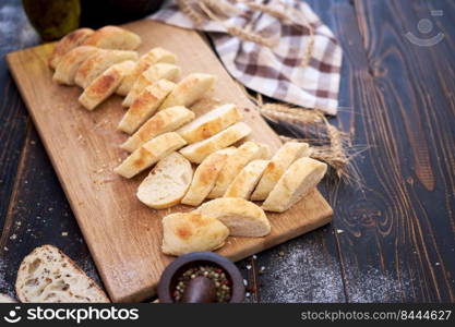 Fresh sliced bread on wooden cutting board at kitchen table.. Fresh sliced bread on wooden cutting board at kitchen table