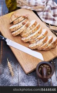 Fresh sliced bread on wooden cutting board at kitchen table.. Fresh sliced bread on wooden cutting board at kitchen table