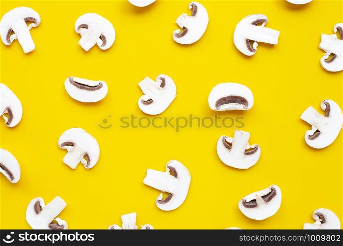 Fresh sliced champignon mushrooms on yellow background. Top view