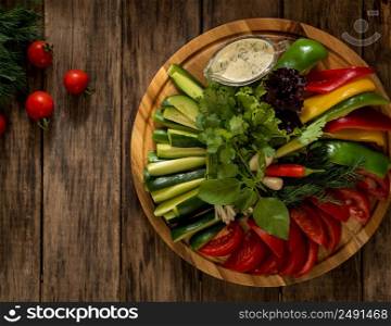 fresh sliced pieces of vegetables on a round tray. assortment of vegetables on a wooden surface, top view. dish on a wooden surface