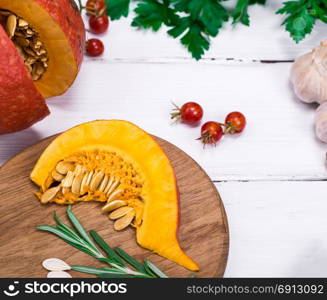 fresh slices of pumpkin and garlic with spices on a white wooden background