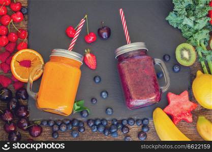 Fresh smoothy berries and orange healthy drink in glass jars with igredients, retro toned. Fresh smoothy orange drink