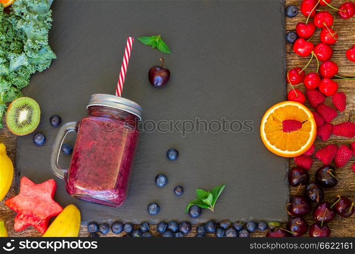 Fresh smoothy berry healthy drink in glass jar with igredients on black. Fresh smoothy berry drink