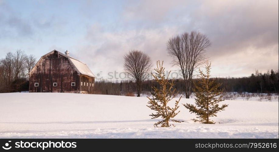 Fresh snow sits on the ground around an old barn