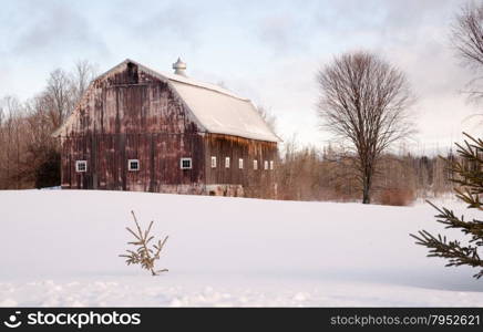 Fresh snow sits on the ground around an old barn