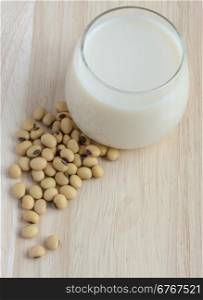 Fresh Soy milk (Soya milk) and dried soybean seeds on wooden background. Traditional staple of East Asian cuisine
