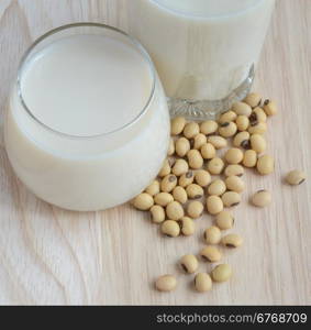 Fresh Soy milk (Soya milk) and dried soybean seeds on wooden background. Traditional staple of East Asian cuisine