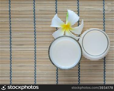 Fresh Soy milk (Soya milk) on bamboo place mat with white plumeria flower. Traditional staple of East Asian cuisine