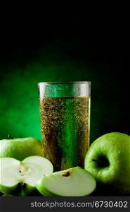 Fresh sparkling green apple juice on green spot lighted background