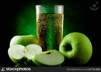 Fresh sparkling green apple juice on green spot lighted background