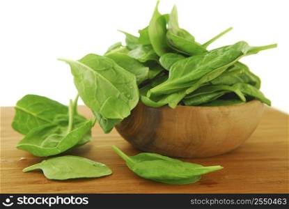 Fresh spinach iin a wooden bowl on a cutting board