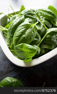 Fresh spinach leaves in a bowl, green vegetables, rustic style, healthy lifestyle, proper nutrition. 