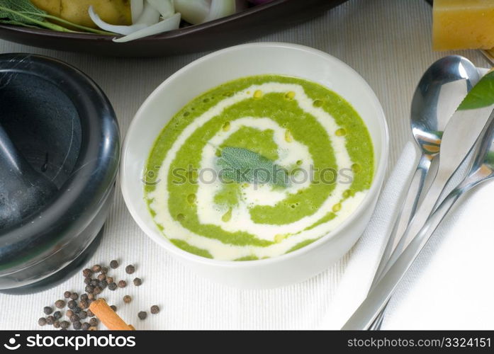 fresh spinach soup on a white bowl with sage and cream on top