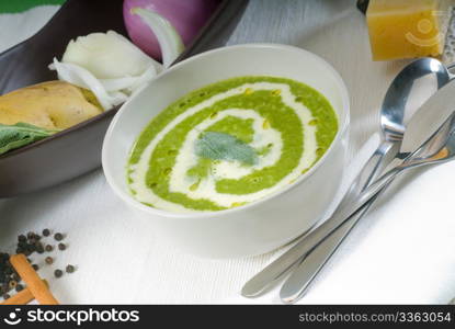 fresh spinach soup on a white bowl with sage and cream on top