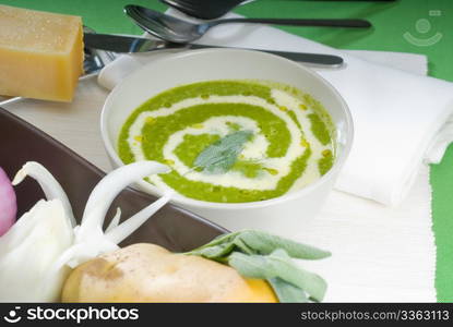 fresh spinach soup on a white bowl with sage and cream on top