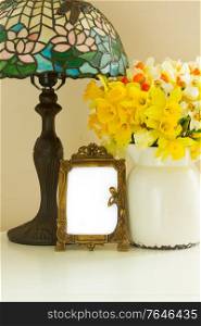 Fresh spring daffodils in white pot on table with empty art nuveau frames. Fresh spring daffodils