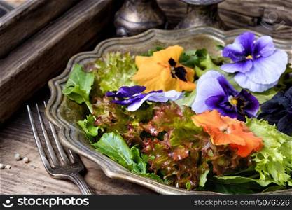 Fresh spring salad with edible flowers. Vegetarian dietary salad with arugula, salad and flowers