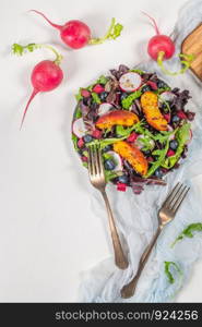 Fresh spring salad with rucola, lettuce, blueberries, radish, beet and slices of peach. White background with free text space