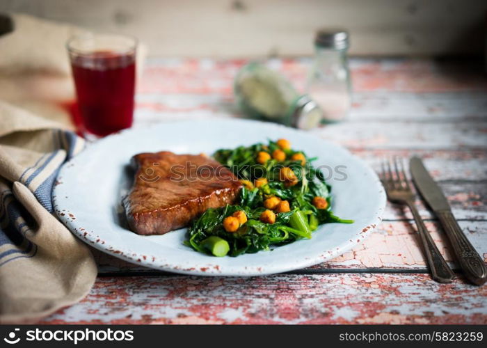 Fresh steak with green salad on rustic wooden background