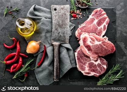 Fresh steaks from Raw pork meat on dark stone background, Top view