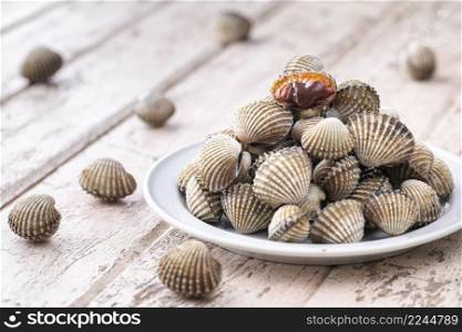fresh steamed cockles, boiled cockles in ceramic plate on old white wood texture background, easy seafood recipe menu, blood cockle