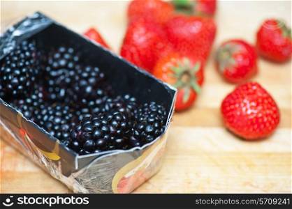 Fresh strawberries and blackberries at wooden background