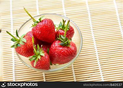 Fresh strawberries in a bowl on bamboo background