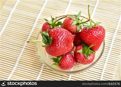 Fresh strawberries in a bowl on bamboo background