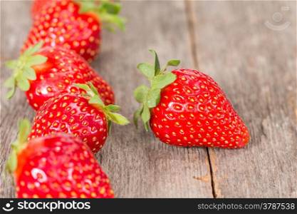 Fresh strawberries in a row on wooden background