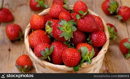 Fresh strawberries in basket spinning on wooden table. Healthy eating concept. Fresh fruits background.